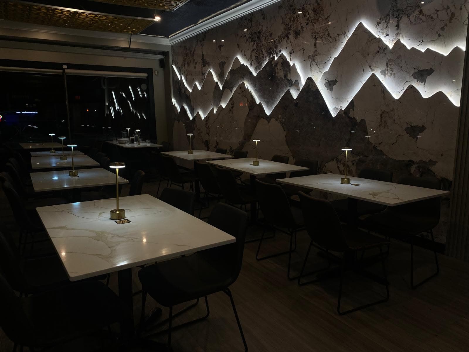 Karakoram Restaurant's dining room set for an evening event, lit beneath the mountain-range feature wall