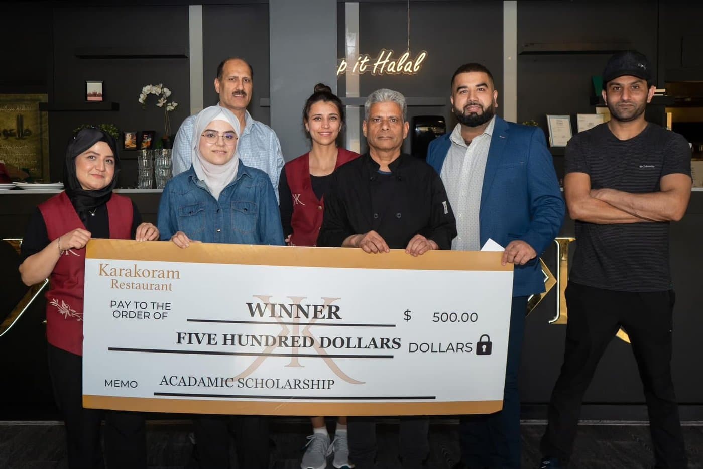 Karakoram Restaurant presenting a $500 academic scholarship cheque to a winning student